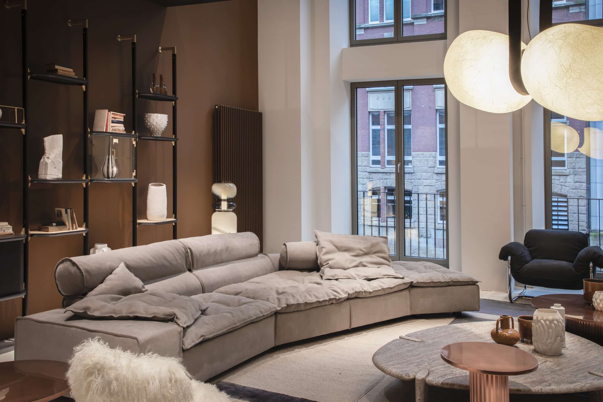 Interior-Showroom zeigt ein Wohnzimmer mit einer Ledercouch, Regalen, kleinen Tischen und hängenden Deckenleuchten
